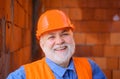 Smiling construction worker in safety vest and hard hat. Bearded engineer, architect builder in protective helmet. House Royalty Free Stock Photo