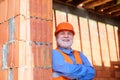 Smiling construction worker in safety vest and helmet at work. Bearded architect builder in protective hard hat