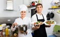 Smiling cook giving to waitress ready to serve salad Royalty Free Stock Photo