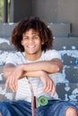 Smiling cool guy sitting outside with skateboard