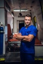 Smiling corpsman in a medical uniform stands with an ambulance car in the background