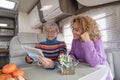 Smiling couple of caucasian women multigenerational family sitting inside a camper van motor home looking at map planning next Royalty Free Stock Photo