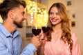 Smiling couple clinking wine glasses, with festive lights Royalty Free Stock Photo