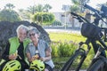 A smiling couple of cyclists have a break in the park eating some fruit. Two electric bicycles close to them. Healthy lifestyle Royalty Free Stock Photo