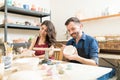 Smiling Couple Doing Creative Painting On Bowls In Pottery Works