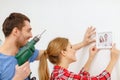 Smiling couple drilling hole in wall at home