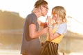 smiling couple drinking beverage with two plastic straws from one bottle on river beach Royalty Free Stock Photo