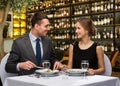 Smiling couple eating main course at restaurant