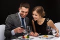 Smiling couple eating main course at restaurant