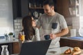 Smiling couple enjoying beautiful morning at home kitchen, starting to work from home in paj