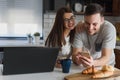 Smiling couple enjoying beautiful morning at home kitchen, starting to work from home in paj