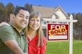 Smiling Couple in Front of Sold Real Estate Sign and House Royalty Free Stock Photo