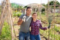 Smiling couple with garden mattock near wooden girders