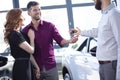 Smiling couple getting car keys from a dealer in a showroom Royalty Free Stock Photo