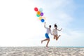 Smiling couple hand holding balloon and jumping together on the beach. Lover romantic and relax honeymoon in summer holiday. Summ