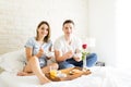 Smiling Couple Having Bowls Of Cereal In Bed