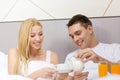 Smiling couple having breakfast in bed in hotel Royalty Free Stock Photo