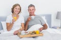 Smiling couple having breakfast in bed together Royalty Free Stock Photo