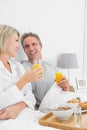 Smiling couple having orange juice at breakfast in bed Royalty Free Stock Photo