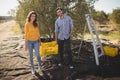 Smiling couple holding crate on sunny day at farm