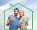 Smiling couple holding money over green house Royalty Free Stock Photo