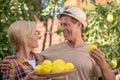Smiling couple holding plate with lemons in the garden