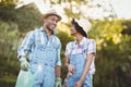 Smiling couple holding watering can and gardening shears