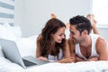 Smiling couple with laptop while lying under blanket Royalty Free Stock Photo