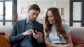 Smiling couple looking mobile phone at home office. Laughing man and woman. Royalty Free Stock Photo