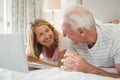 Smiling couple lying on bed and using laptop Royalty Free Stock Photo