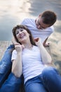 Smiling couple lying on the bridge on the shore of the lake at sunset Royalty Free Stock Photo