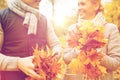 Smiling couple with maple leaves in autumn park