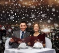 Smiling couple with menus at restaurant