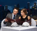 Smiling couple with menus at restaurant