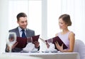 Smiling couple with menus at restaurant