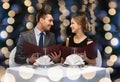 Smiling couple with menus at restaurant