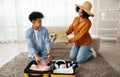 A smiling couple is packing for a trip, with the woman handing clothes to the man who is organizing the suitcase Royalty Free Stock Photo