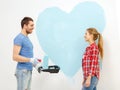 Smiling couple painting big heart on wall Royalty Free Stock Photo