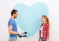 Smiling couple painting big heart on wall Royalty Free Stock Photo