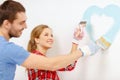 Smiling couple painting small heart on wall Royalty Free Stock Photo