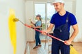 Smiling couple painting wall with paint roller and paintbrush at Royalty Free Stock Photo