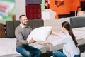 smiling couple with pillow in furniture store