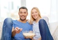 Smiling couple with popcorn watching movie at home