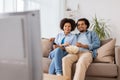 Smiling couple with popcorn watching tv at home Royalty Free Stock Photo