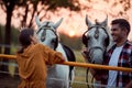 Smiling couple on the ranch at sunset preparing their horses for a ride Royalty Free Stock Photo