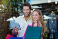 Smiling couple with shopping bags holding tablet computer Royalty Free Stock Photo