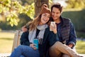 Smiling Couple Sitting On Bench In Autumn Park Using Mobile Phone Royalty Free Stock Photo