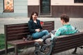 Smiling couple sitting on bench talking to each other drinking coffee Royalty Free Stock Photo