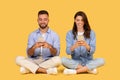 Smiling couple sitting cross-legged, engrossed in their smartphones Royalty Free Stock Photo