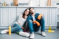 smiling couple sitting on floor and leaning on kitchen counter after cleaning Royalty Free Stock Photo